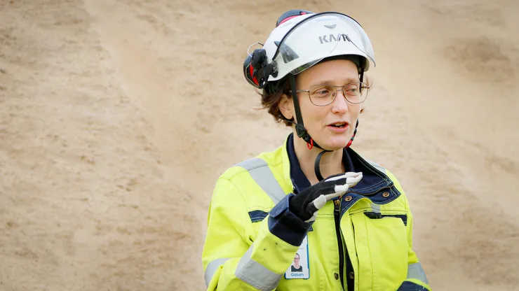 Kvinna i arbetskläder och hjälm.