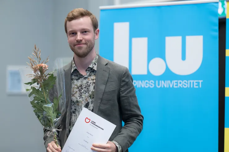 Person poserar med blomma och diplom