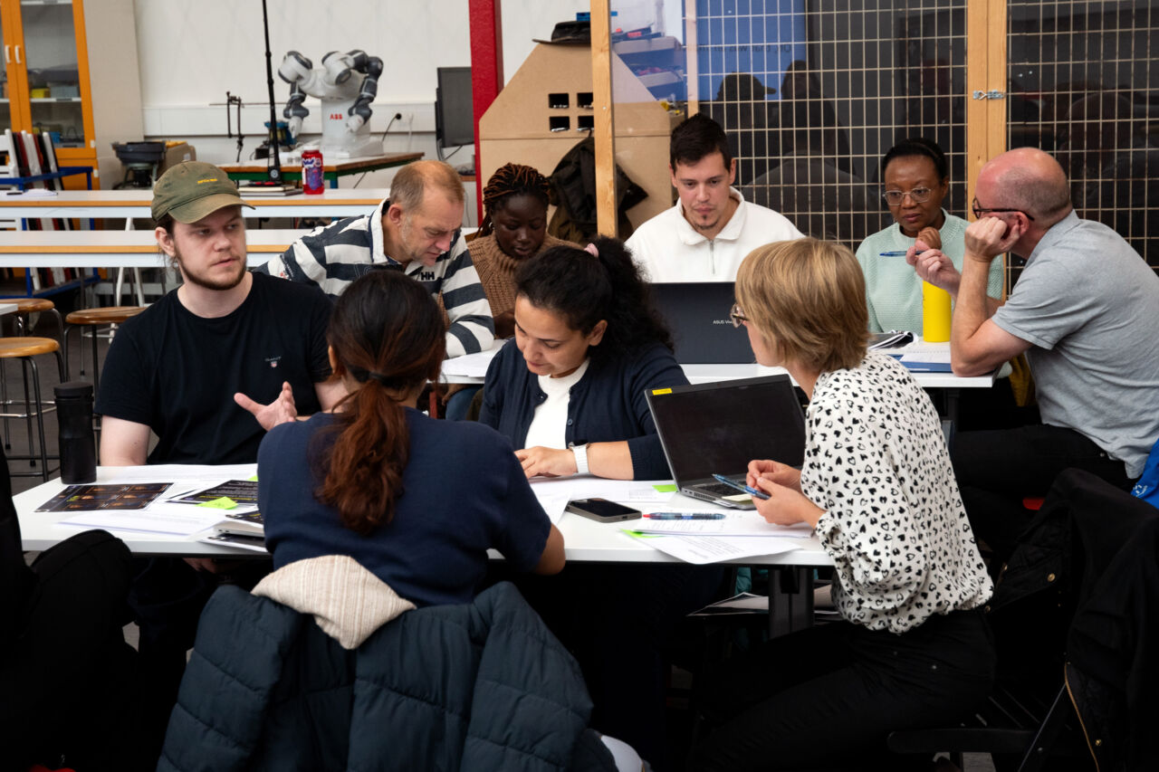  Nine participants sitting at two tables. 