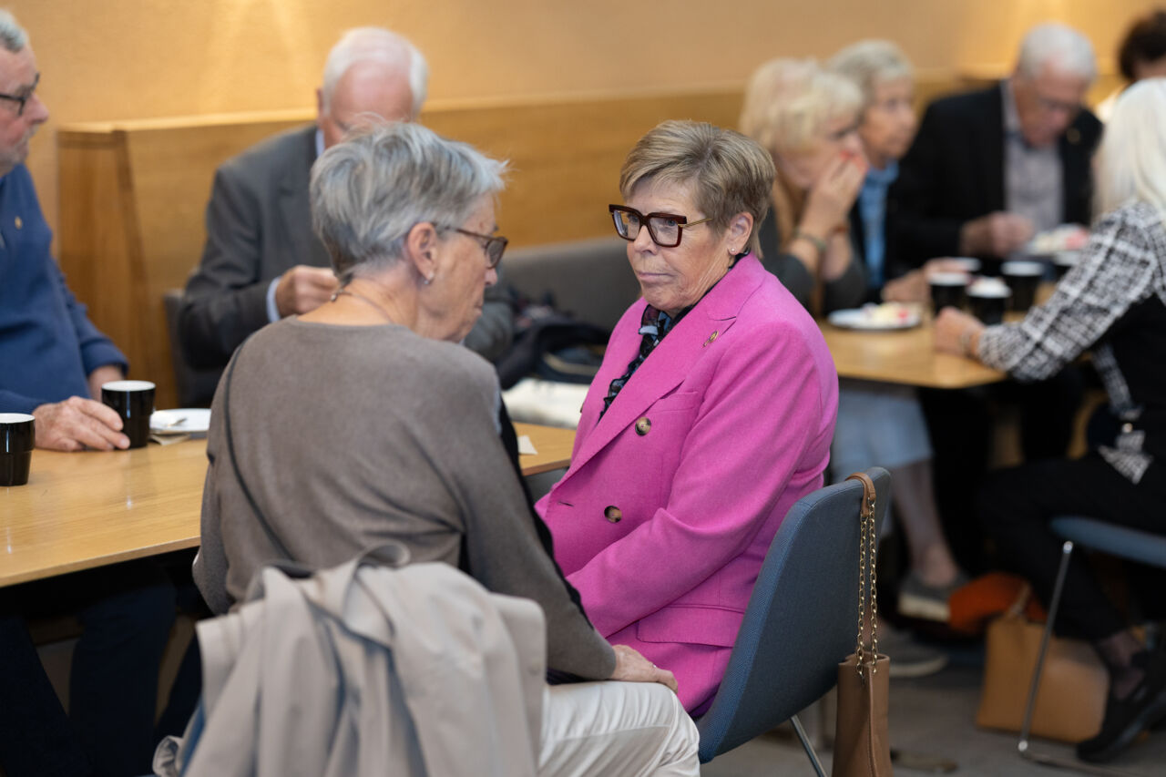 Mingel, samtal och kaffe när två damer sitter och pratar vid ett bord.