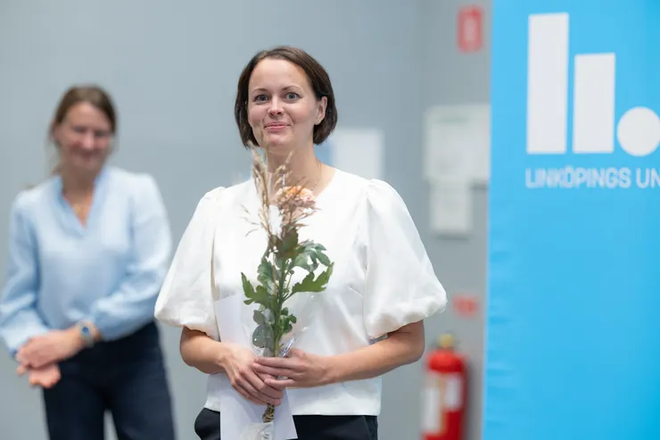 person poserar med blomma och diplom