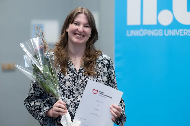 person poserar med blomma och diplom