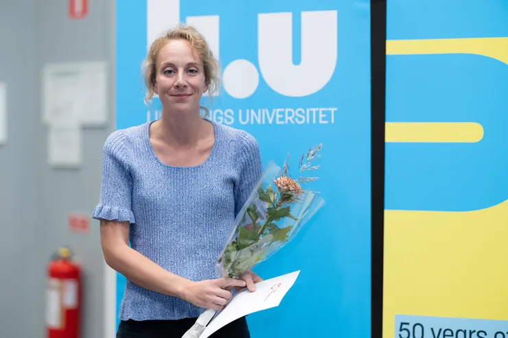 person poserar med blomma och diplom