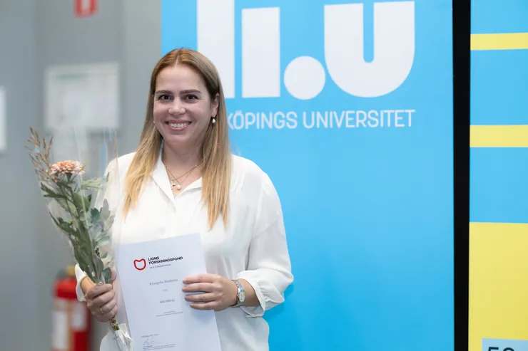 person poserar med blomma och diplom