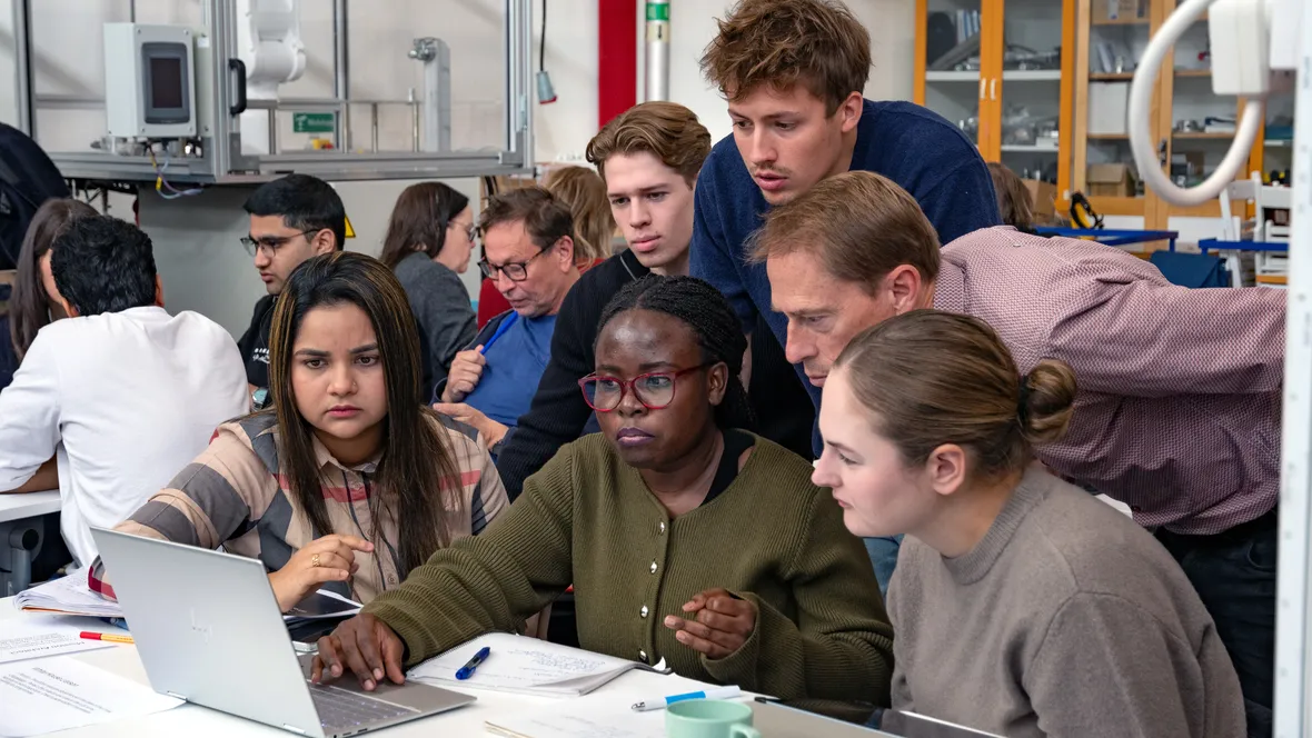 Sex personer, tätt ihop, tittar på en dator tillsammans. 