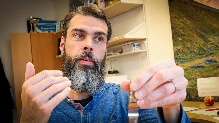 Manlig professor visar olika mekaniska brott på metallföremål.