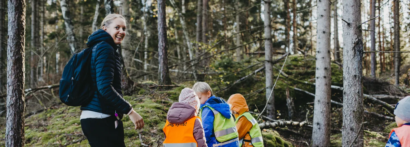 En grupp barn med sin lärare i skogen.