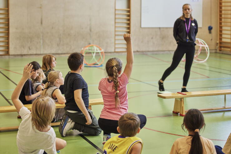 En lärare och elever i en idrottssal.