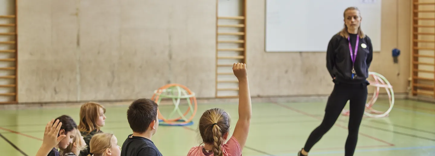 En lärare och elever i en idrottssal.