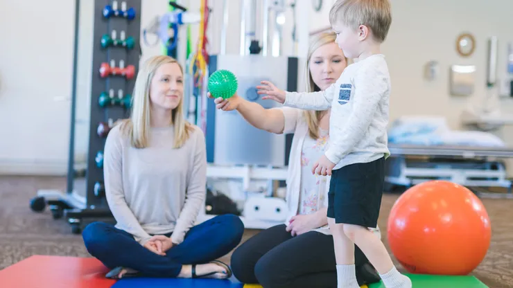 Liten pojke gör övningar hos fysioterapeut