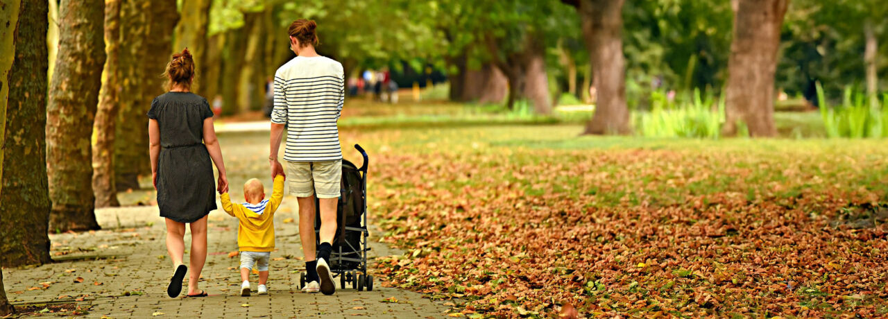 Familj som promenerar i höstlandskap.