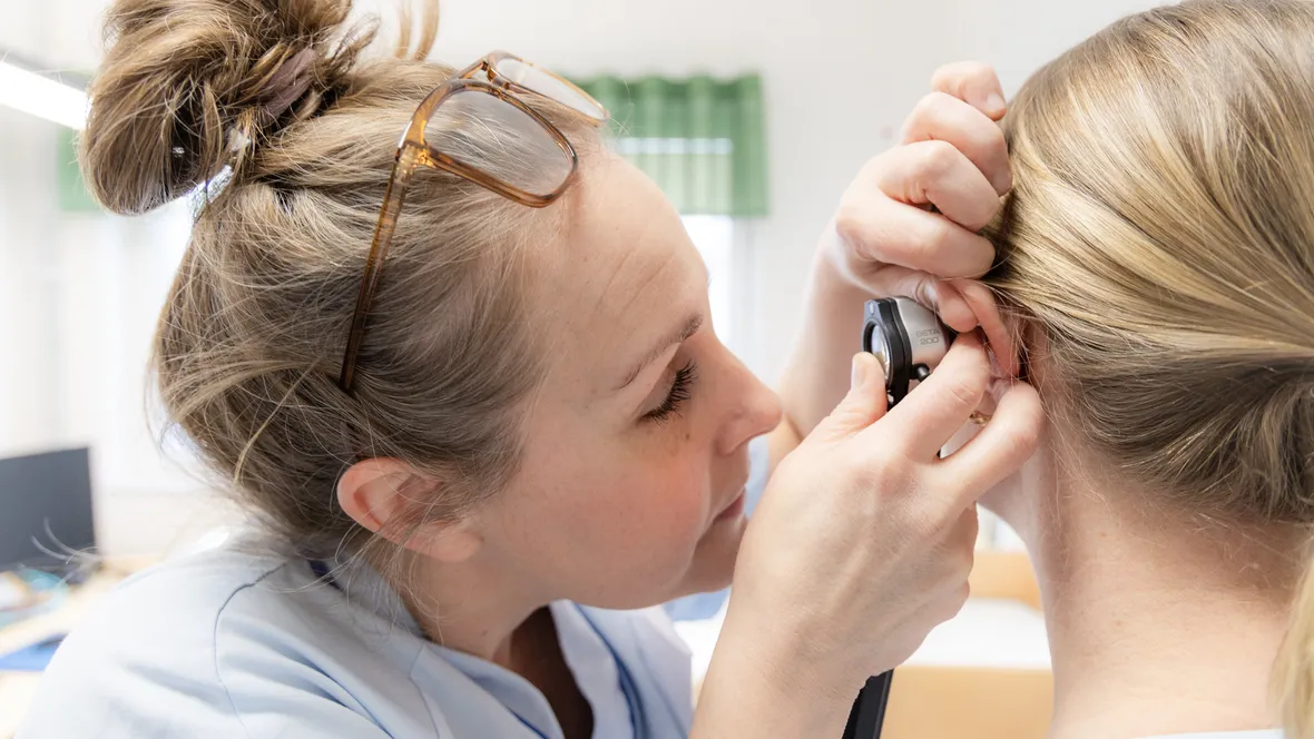 Sjuksköterska tittar i örat på patient.