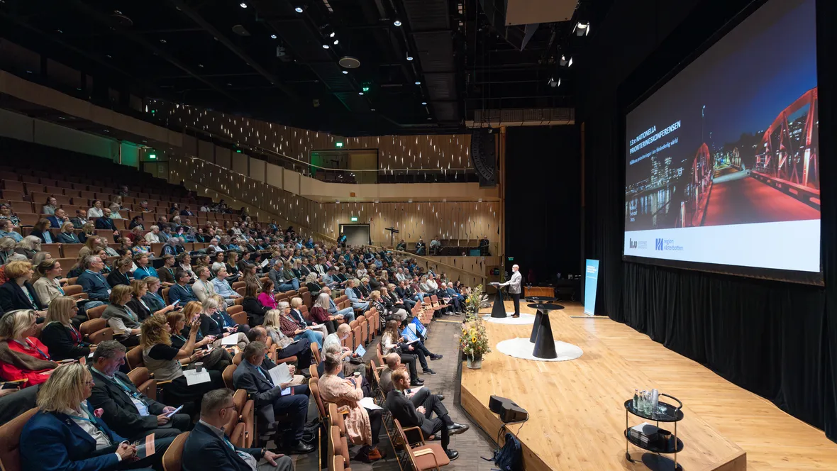 Deltagare och talare i stor aula. 