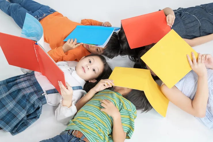 Några barn som ligger på golvet och läser böcker.