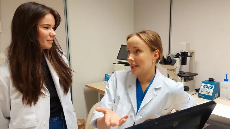 Två unga kvinnor diskuterar på lab.