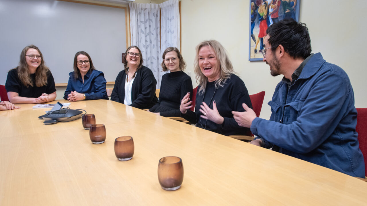 Deltagare sitter vid ett bord och diskuterar.