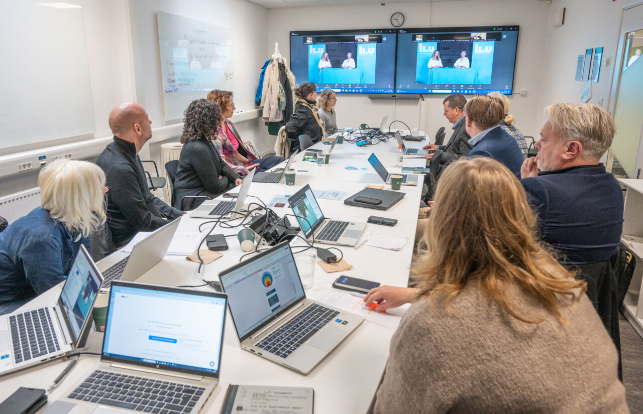 Deltagare sitter vid ett bord och följer konferensen digitalt.