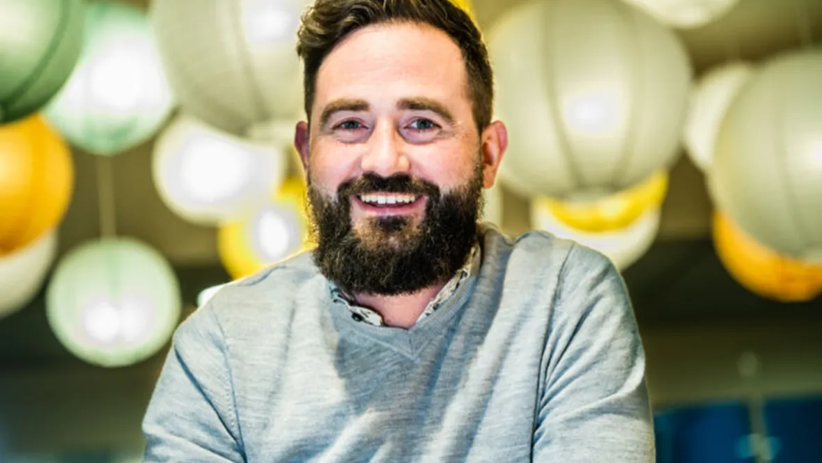 Man med mörkt hår mot blurrig kontorsbakgrund