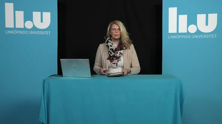 Forskare håller en digital föreläsning med en dator på bordet framför sig.