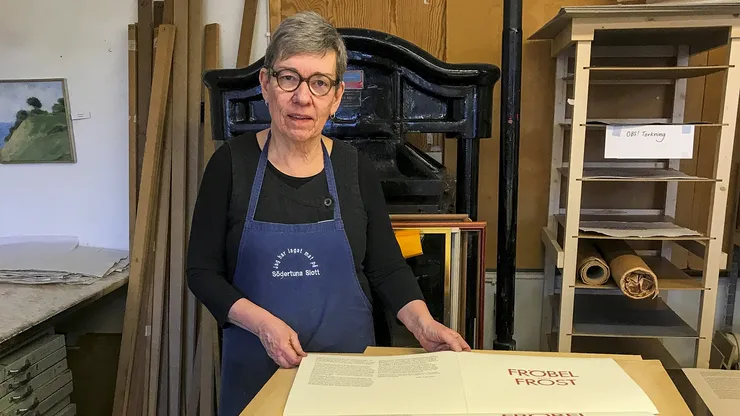 En kvinna i en ateljé som håller i ett kostverk.