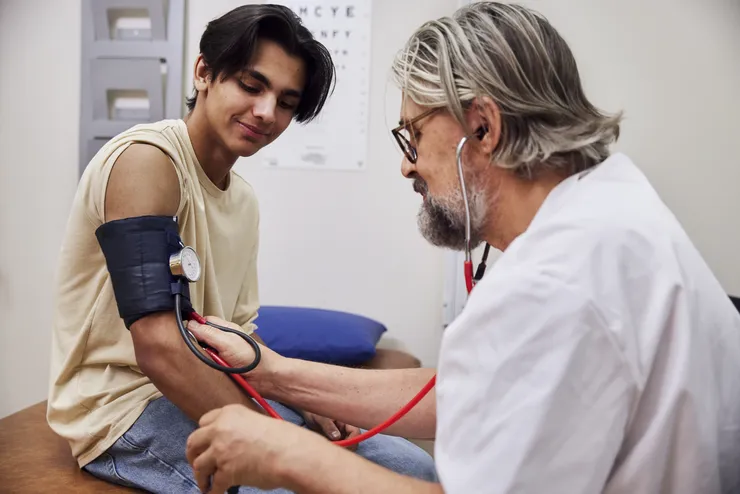 Läkare mäter blodtrycket på en ung man.