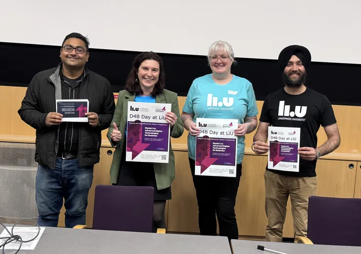 Fyra människor som står på scen och ler och håller upp papper