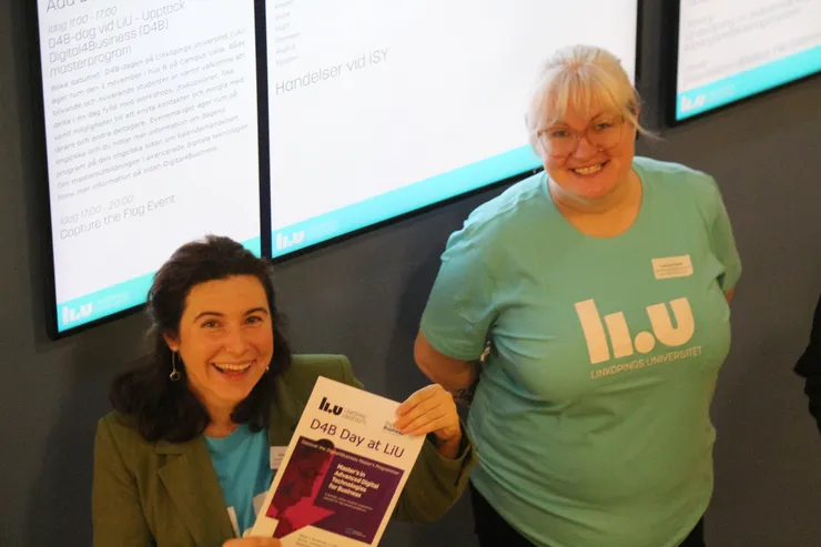 Two women smiling and holding up papers