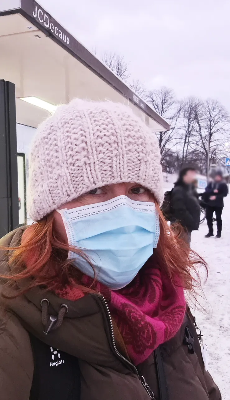 Lady with mas at a bus stop.
