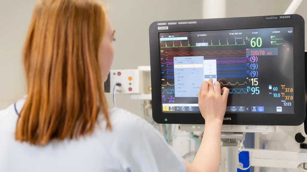 Kvinna kontrollerar övervakningsskärm på intensivvårdsavdelning.