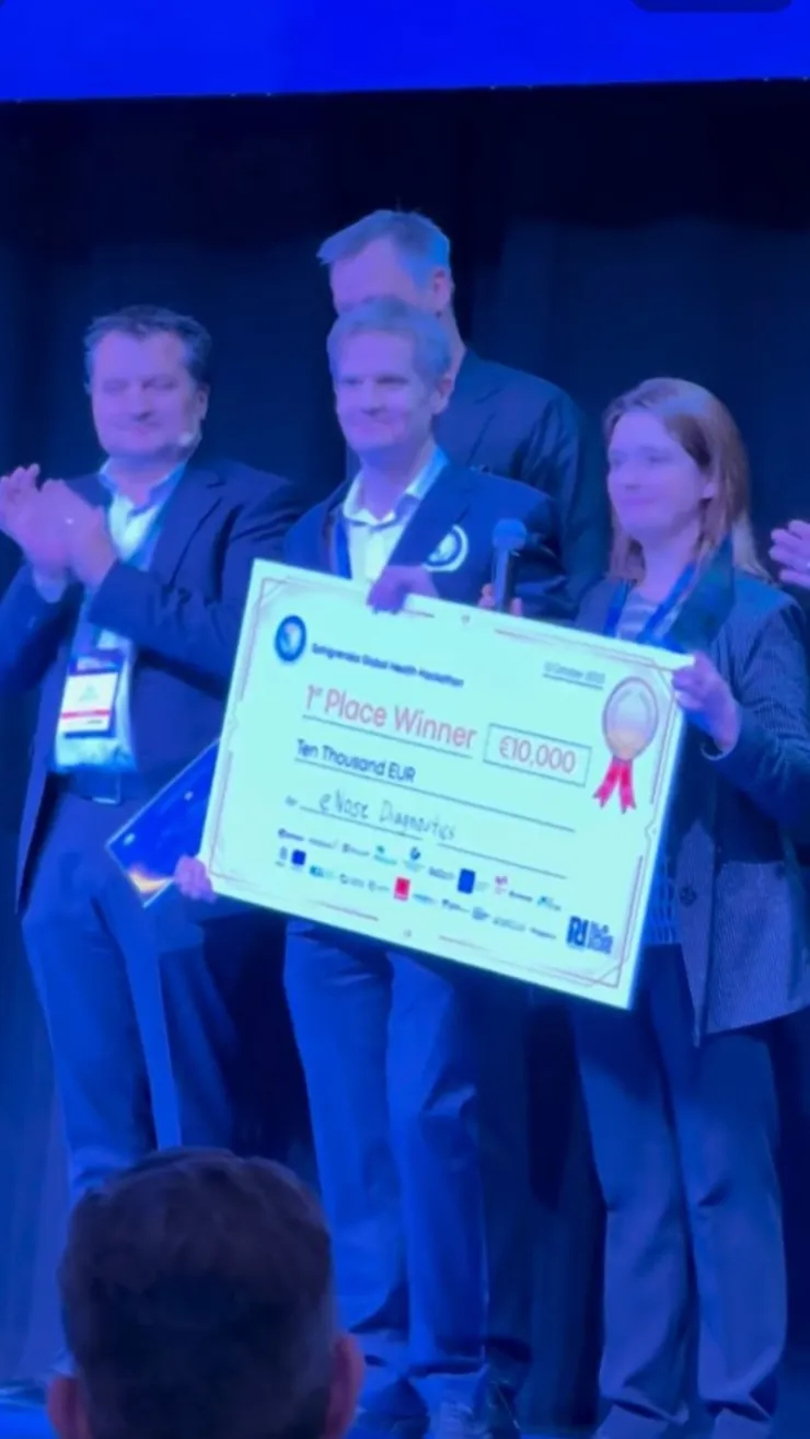 still photo from a video showing three people behind an oversized prize check