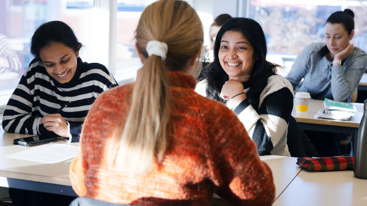 Kvinnor ler i klassrumsmiljö.