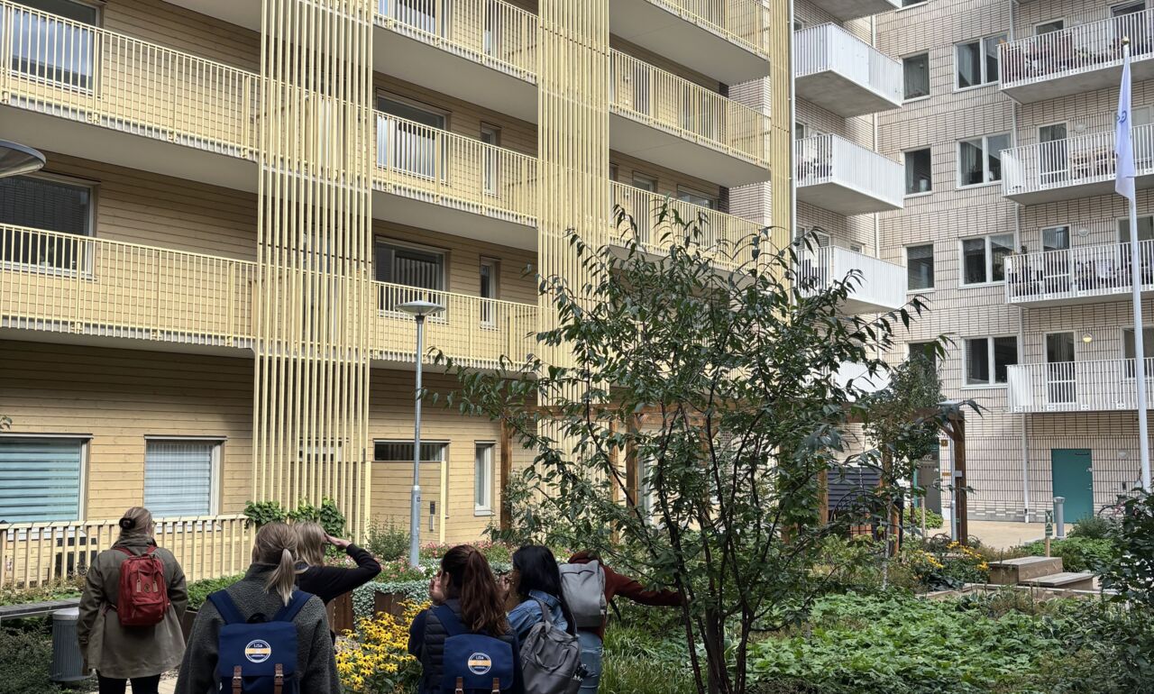 En grupp personer står och tittar på höga byggnader.