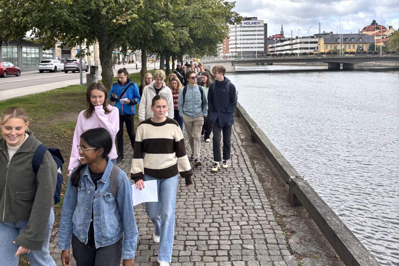 Personer går bredvid en ström i en stadsmiljö.