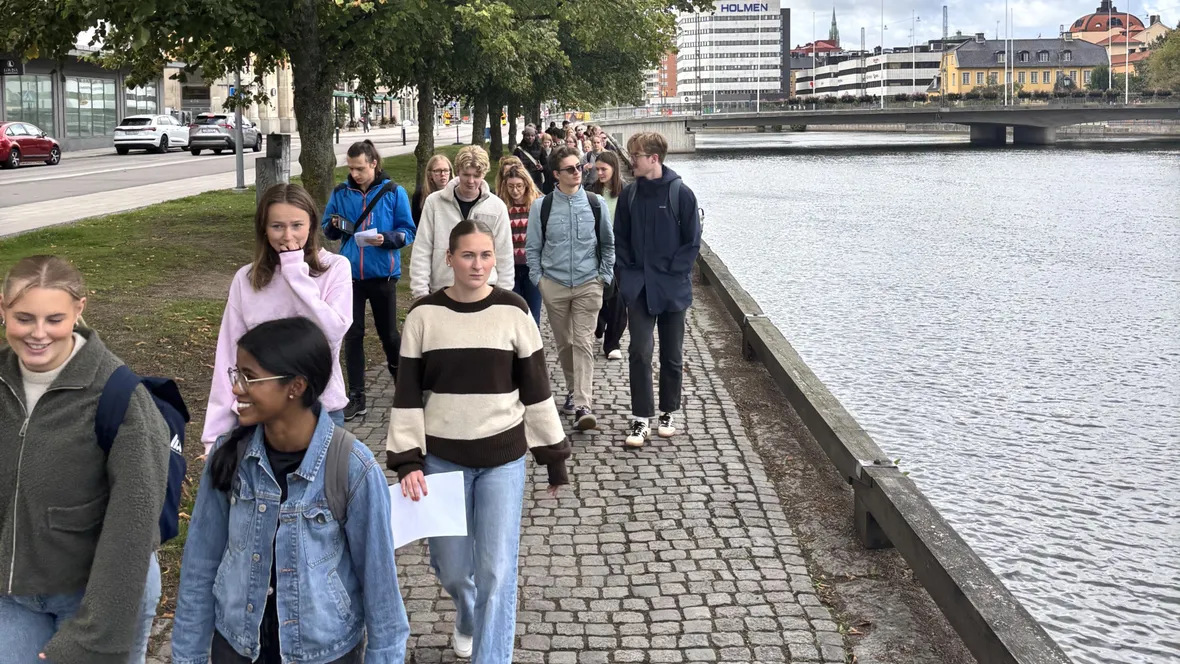 People are walking beside a stream in an urban environment.