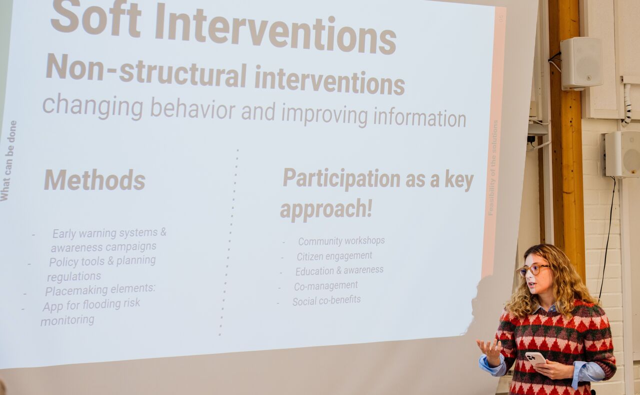 Kvinna står i en lärosal vid en filmduk.