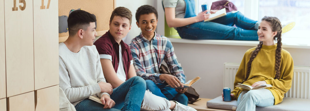 Multikulturella leende skolbarn som har kul under skolan paus.