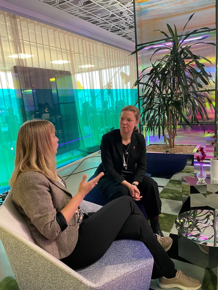 Två kvinnor sitter i stolar och samtalar i ett kontor.