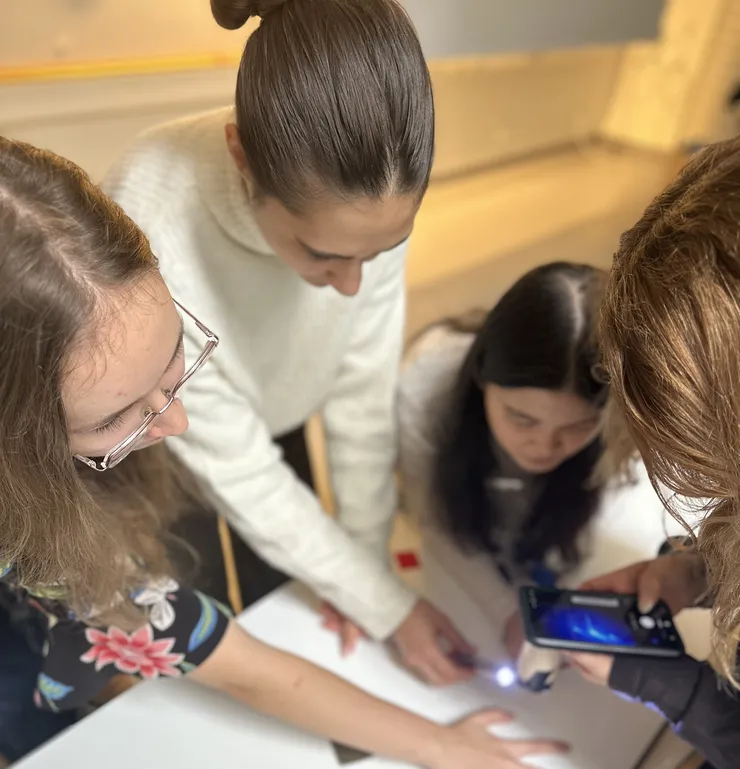 Fyra kvinnor lutar sig över ett bord