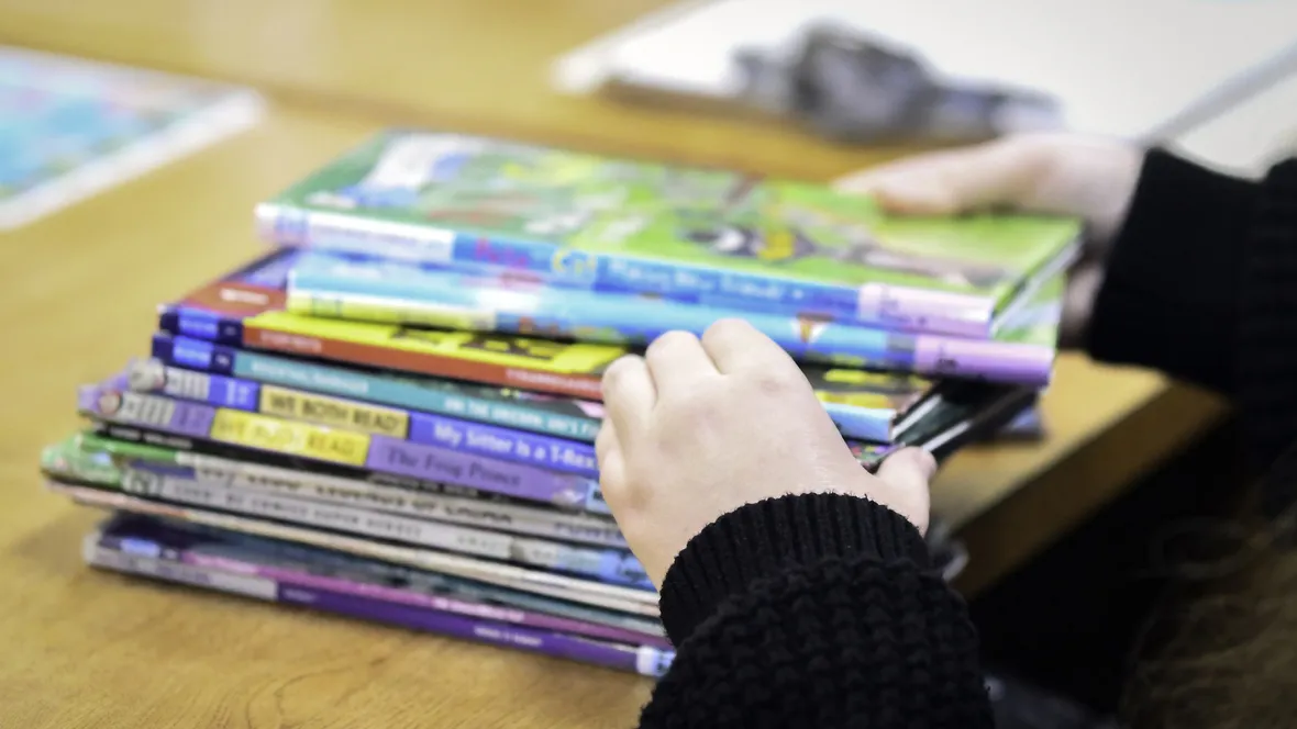 Ansiktslöst porträtt av bibliotekarie som sorterar barnböcker.