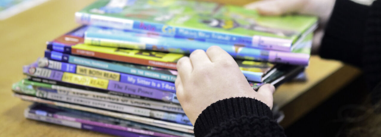 Ansiktslöst porträtt av bibliotekarie som sorterar barnböcker.