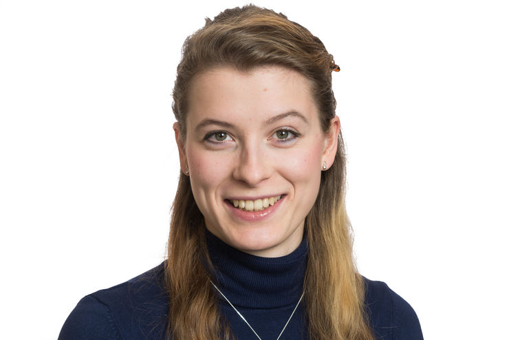 Smiling woman with long hair and black turtleneck looks into the camera.