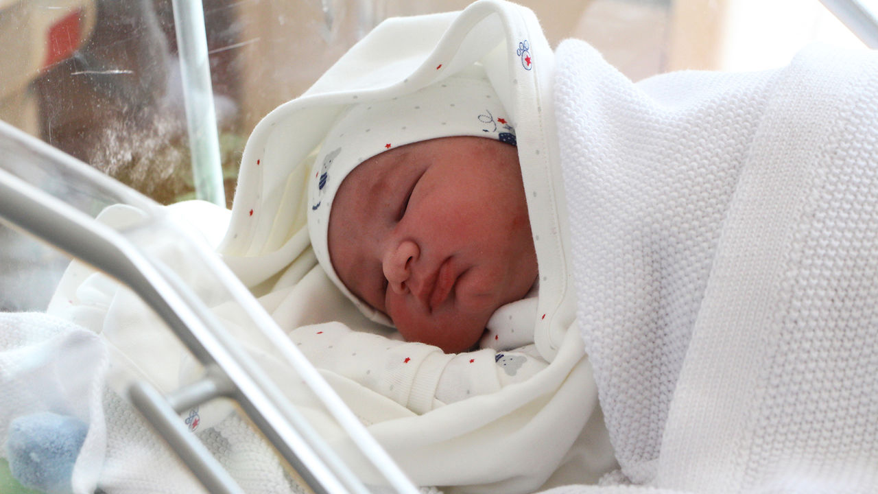 En nyfödd bebis som ligger under en filt.