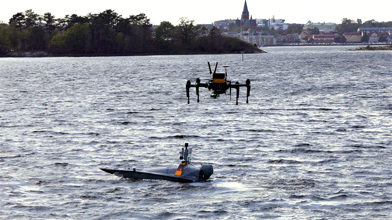 A boat in the water and a drone in the air above it.