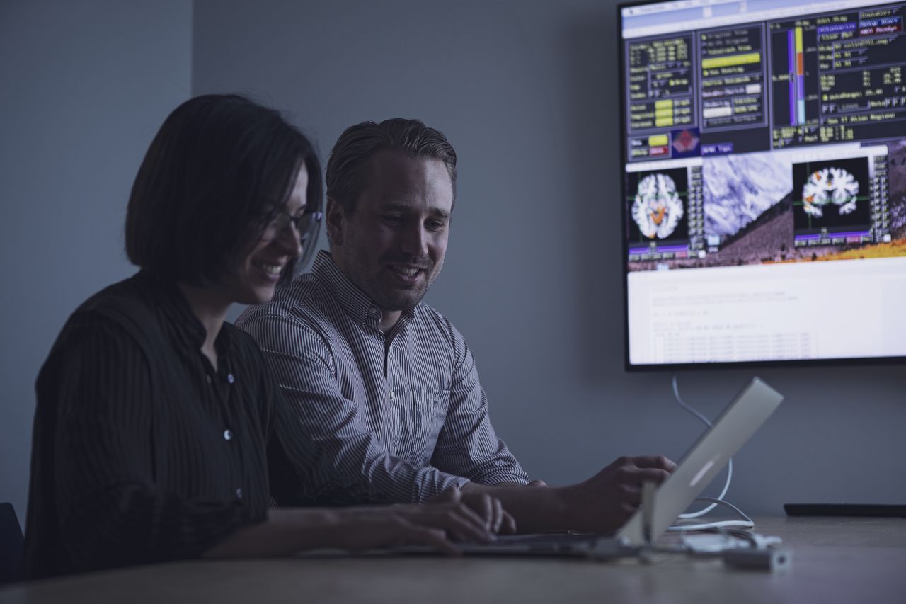 Two researchers are looking at a laptop