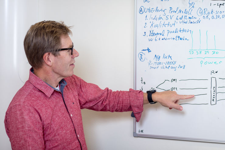 Statistikern Mats Fredrikson pekar på en whiteboardtavla.