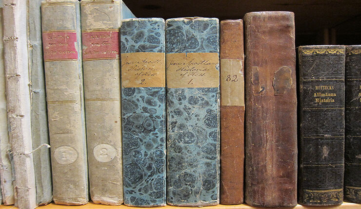 Äldre böcker som står på en hylla.