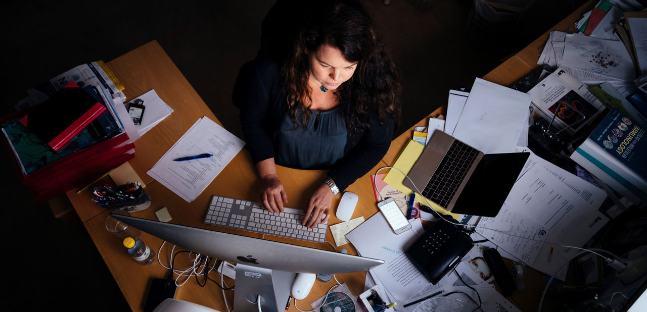 A person at a writing desk seen from above.