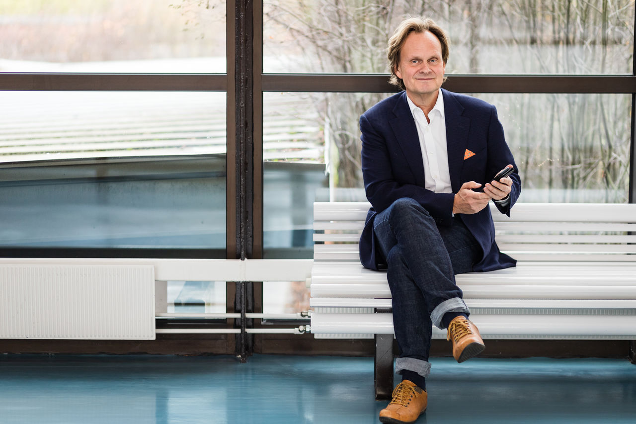 Magnus Blinge sitting on a bench with a cell phone in his hands.
