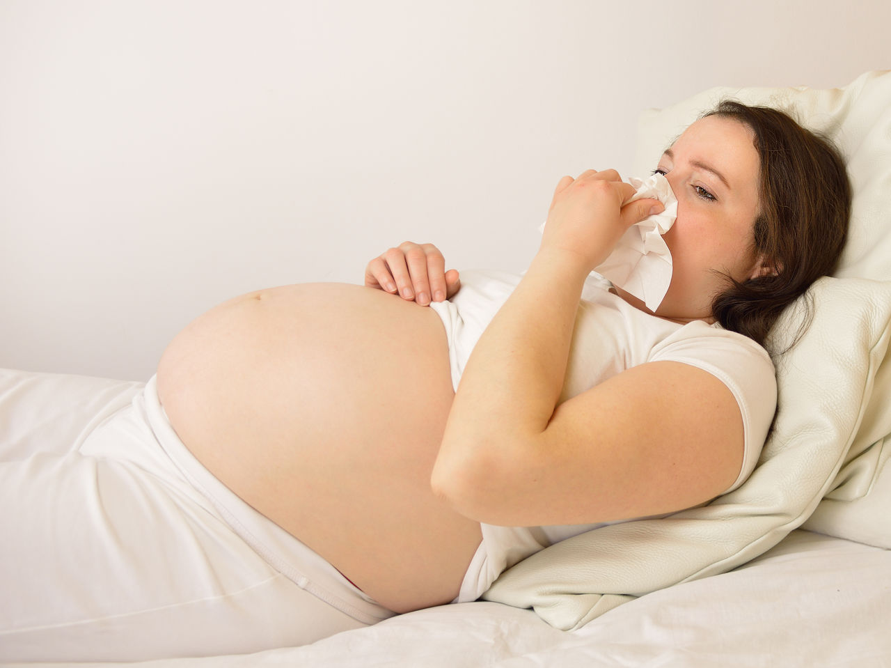 Pregnant woman with cough on the bed in her room