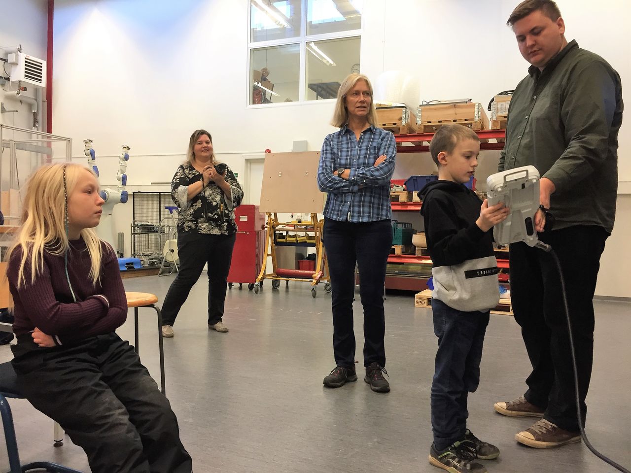 man visar skolbarn robot